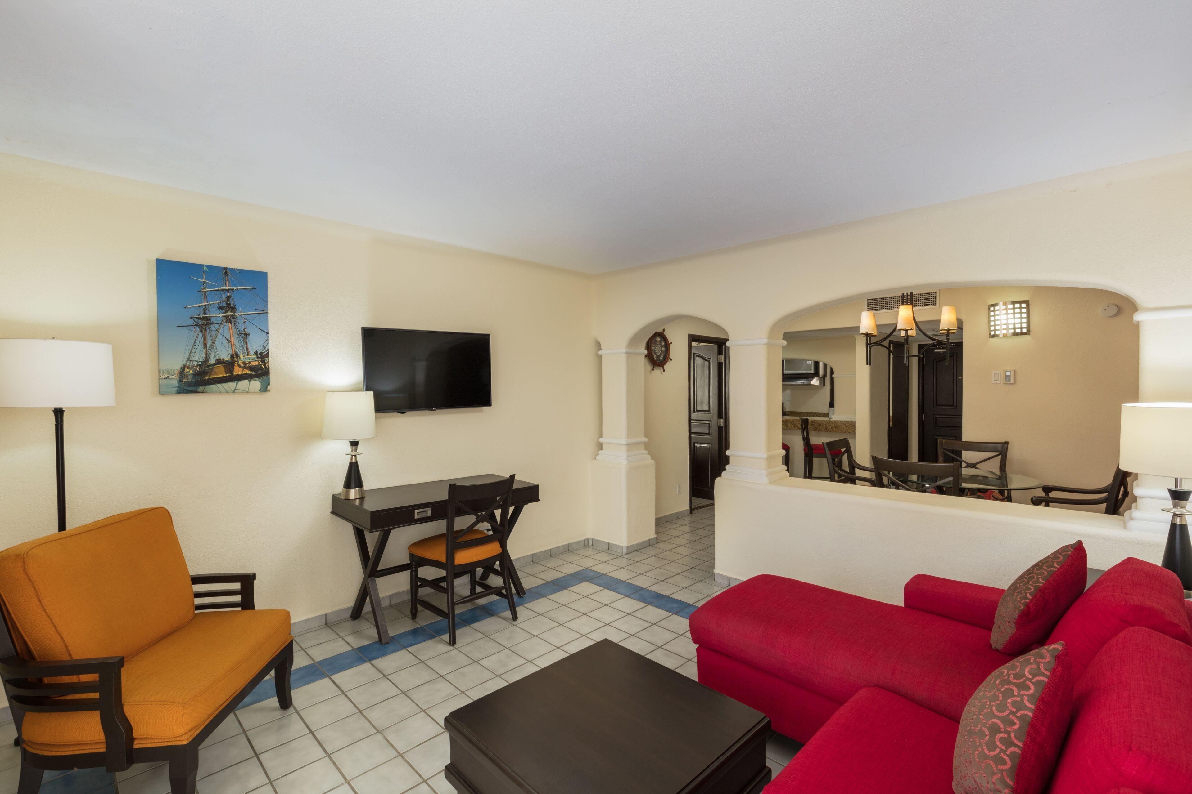 A living room with a sofa, a chair, a dining table, and a TV.