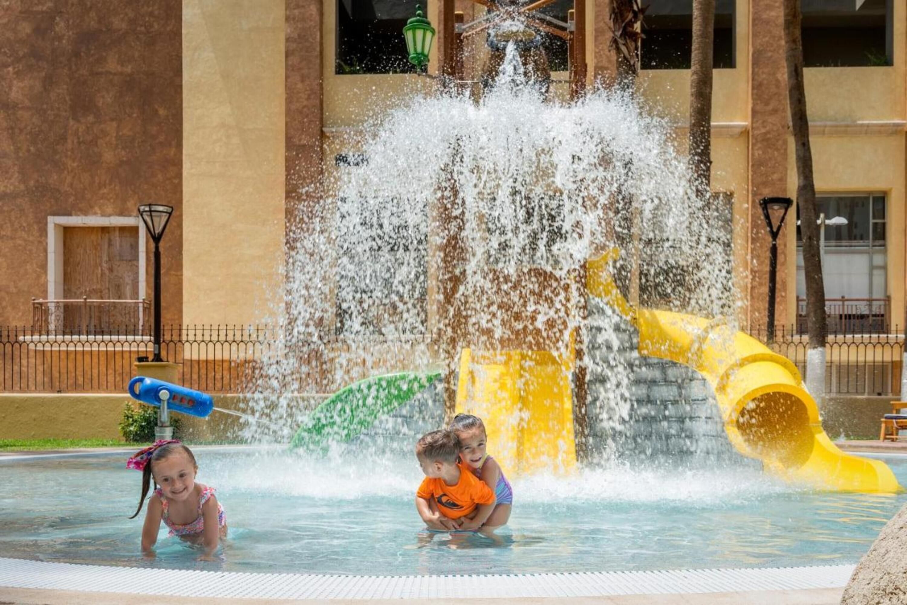 A water play area with a yellow slide and a water fountain.