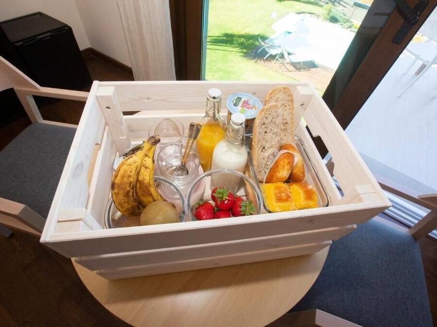 A wooden tray with food items including bread, bananas, yogurt, and strawberries on a table.