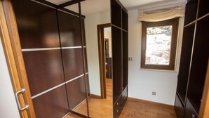 A room with a sliding door closet, a window with a view of a rocky landscape, and a wooden floor. - A Ballenera de Caneliñas (Cee)