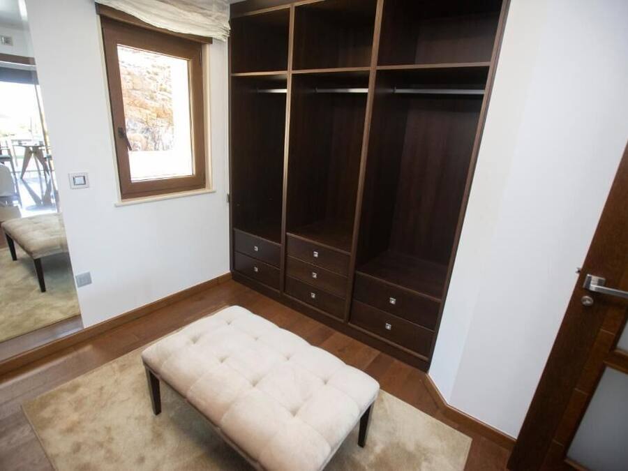 A bedroom with a large closet, a window, and a bench.
