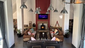 Un salon moderne avec une cheminée, des canapés en cuir et des luminaires suspendus.