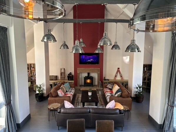A modern living room with a fireplace, leather sofas, and pendant lighting.