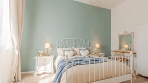 A bedroom with a white metal bed frame, two bedside tables with lamps, a mirror, and a dresser. - Belvilla by OYO Maison (Fucecchio)