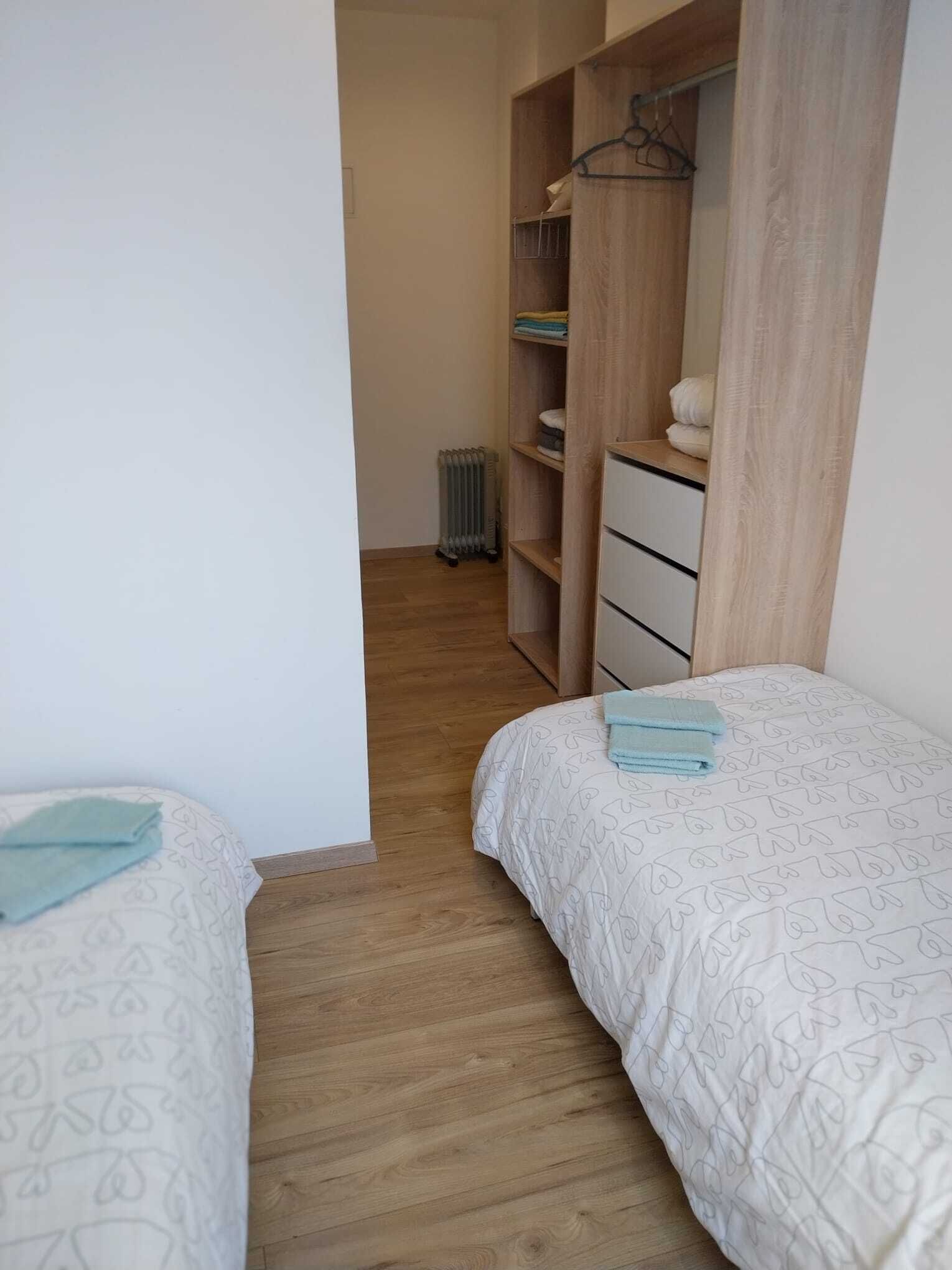 Un dormitorio con dos camas, un armario de madera y un radiador.