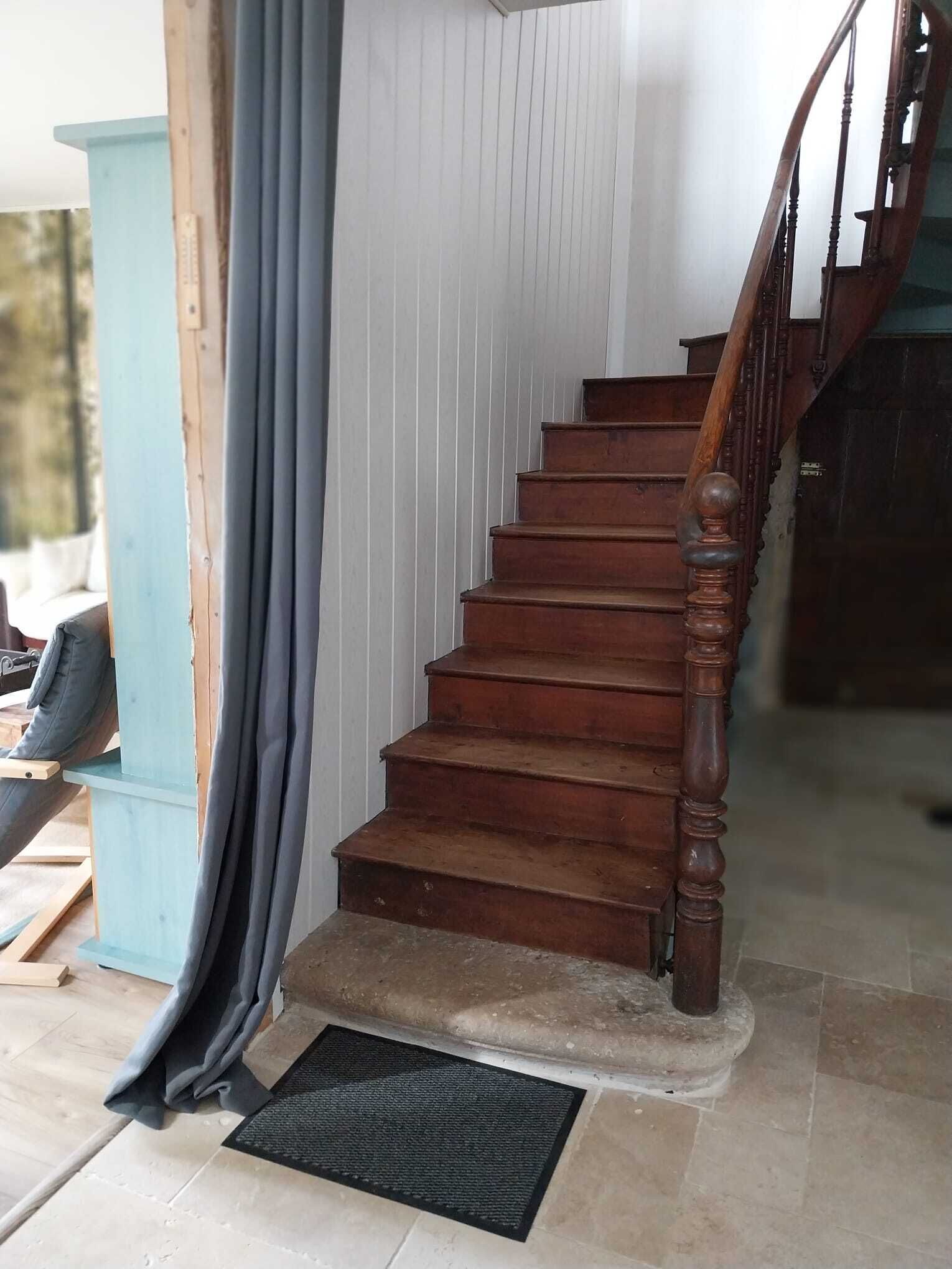 A wooden staircase with a handrail, leading to an upper level.