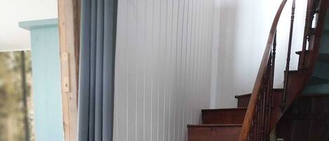 A wooden staircase with a handrail, leading to an upper level.
