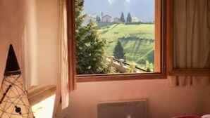 A bedroom with a large window offering a view of a mountainous landscape.
