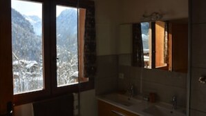 A bathroom with a large window, a mirror, and a sink.