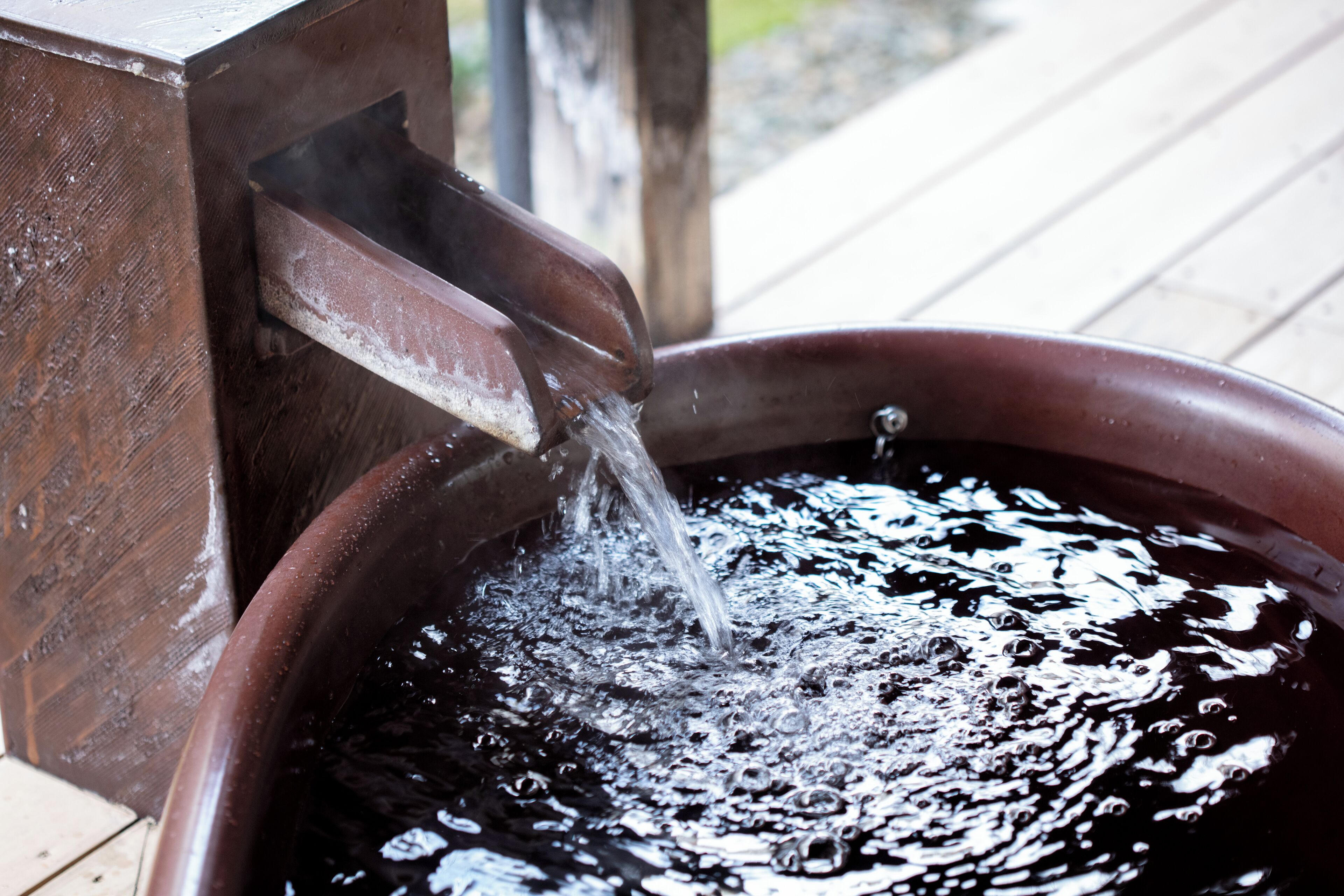 A wooden water feature with water flowing into a circular basin.