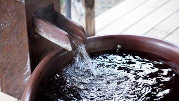 A wooden water feature with water flowing into a circular basin.
