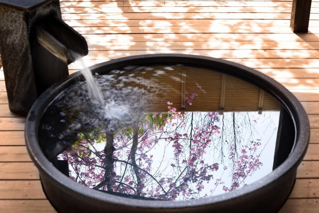 A circular water feature with a bamboo screen, set on a wooden deck.