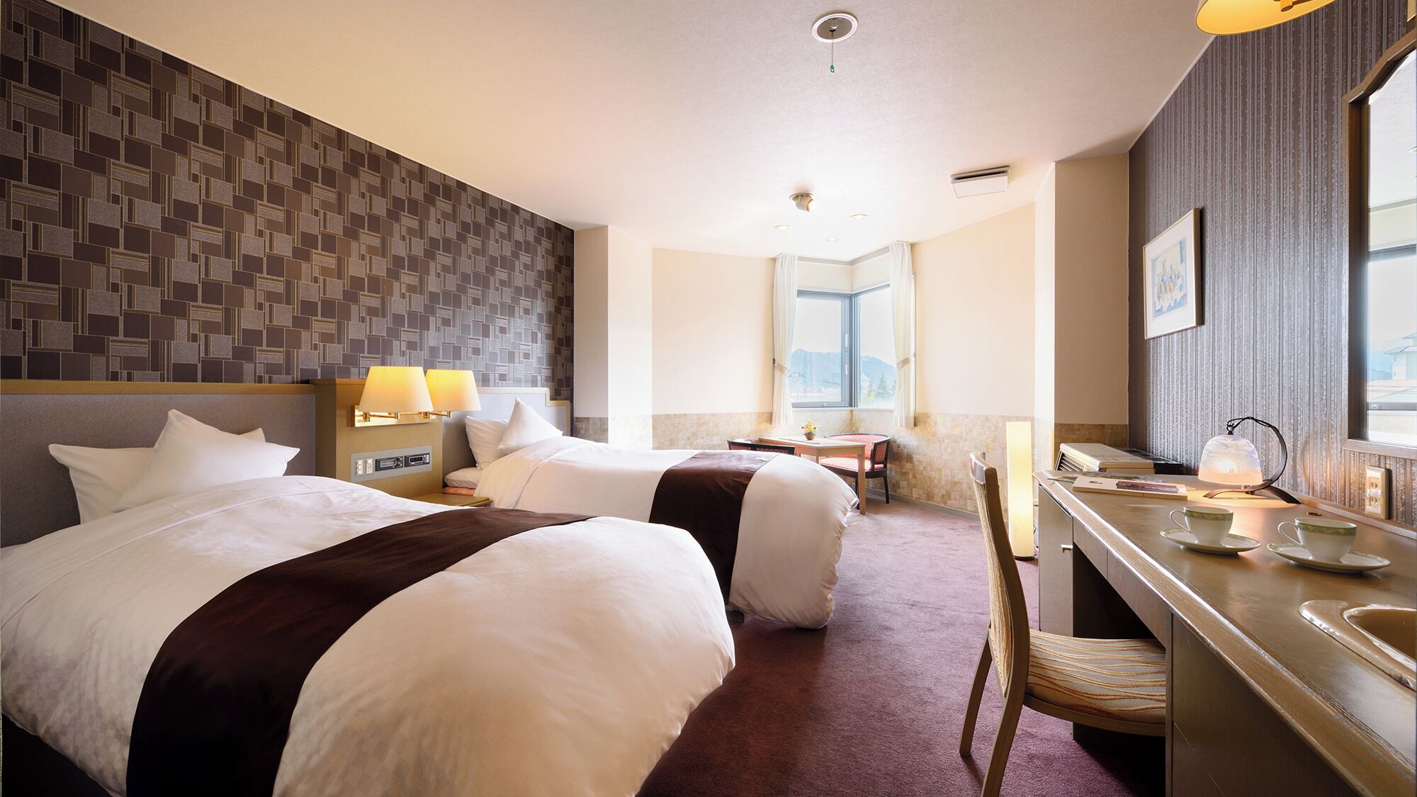 Une chambre d’hôtel avec deux lits, un bureau, une chaise, une fenêtre et une vue sur l’extérieur.