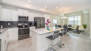 A modern kitchen with white cabinets, stainless steel appliances, and a central island with bar stools. - 3121-406 · Modern Apartment with Privilage Location & View (Kissimmee)