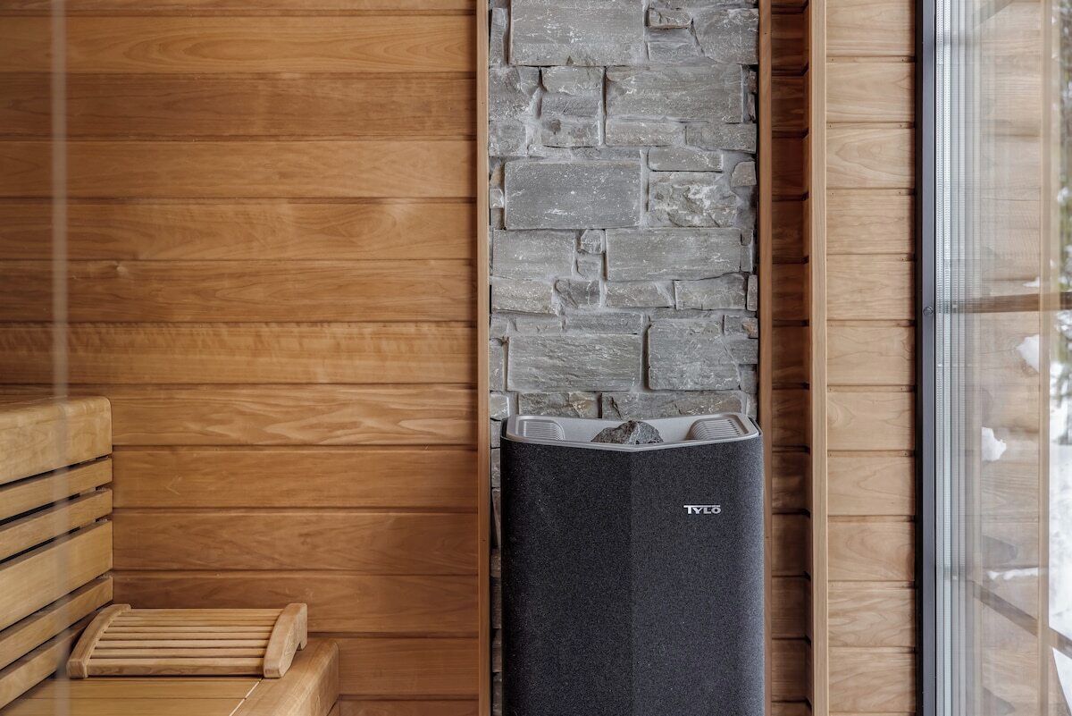 A sauna with a stone wall and wooden benches.