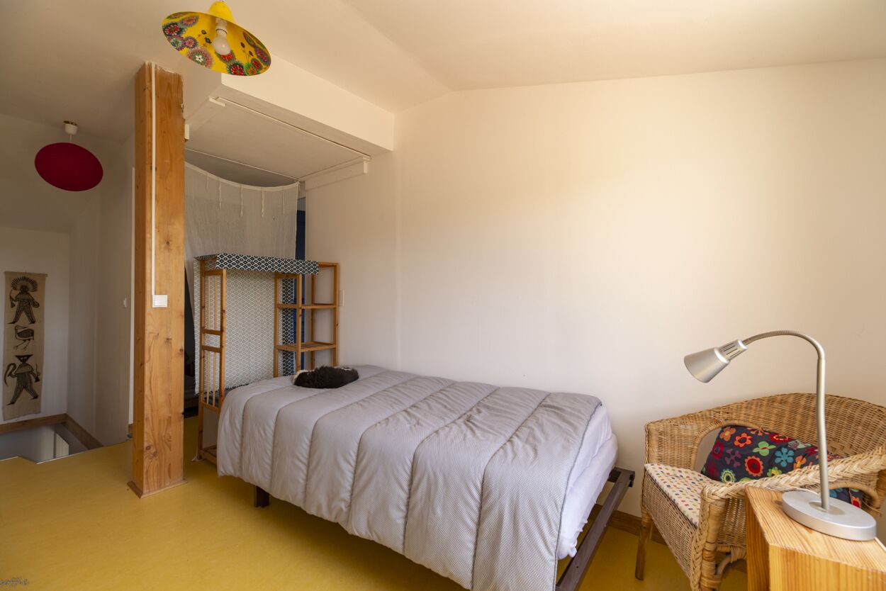 Ein Zimmer mit einem Bett, einem Sessel, einem Schreibtisch und einer Leiter.