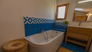 A bathroom with a bathtub, wooden vanity, and blue patterned tiles.