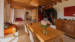 A spacious living area with a wooden dining table, a sofa, and a kitchen in the background.