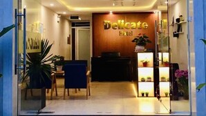 L’entrée de l’hôtel Delicate se distingue par son comptoir d’accueil, ses plantes en pot et son aménagement intérieur moderne.