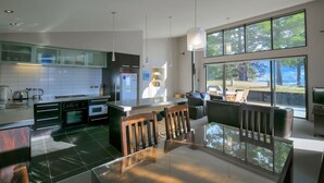 A modern kitchen with a dining area, large windows, and a view of the outdoors. - Anderson Heights | Spacious Stay with lake views (Wānaka)