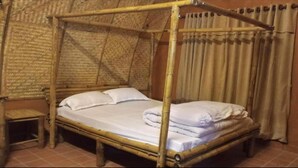 Una cama con dosel con ropa de cama blanca, una mesita de noche de madera y un fondo de cortina.