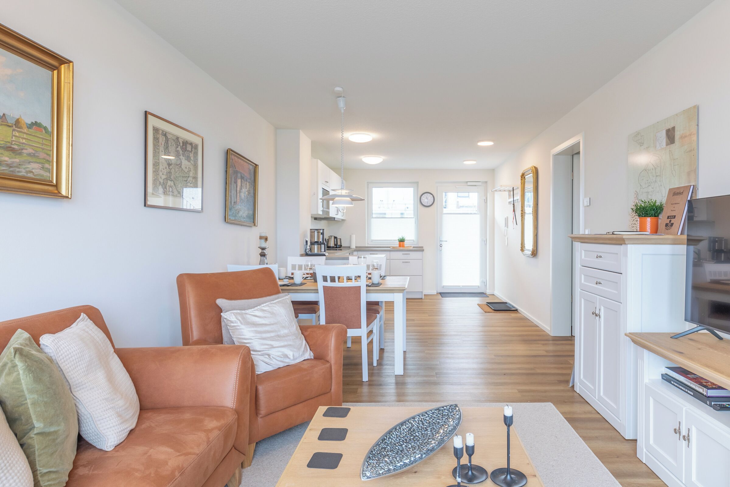 A modern living room with a brown leather sofa, a coffee table, and a dining area with white chairs and a table.