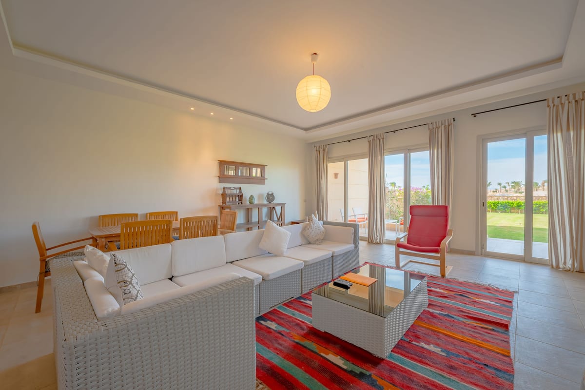 Uma sala de estar moderna com um sofá branco, uma mesa de centro e um tapete colorido.
