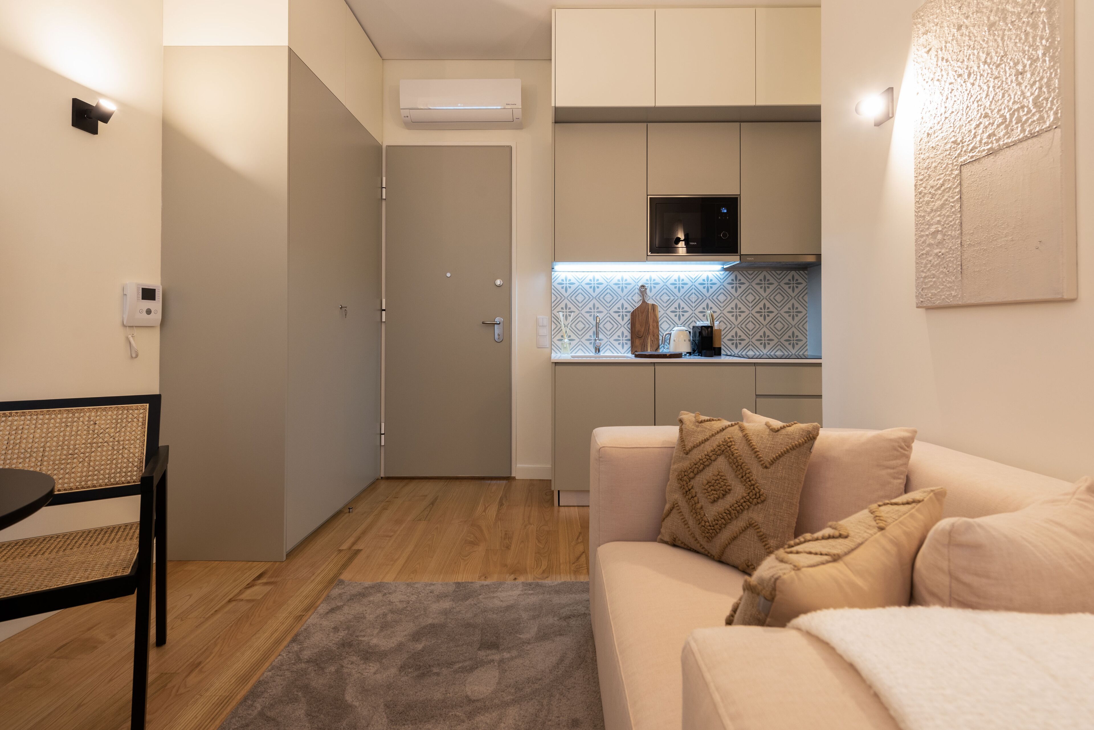 Um espaço compacto com cozinha compacta, área de jantar e área de estar com sofá e poltrona.
