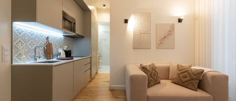 A modern kitchen with a built-in oven, a wooden cutting board, and a kettle on the counter.