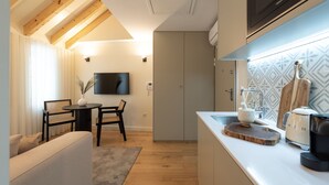 Una cocina moderna con techo de madera, zona de comedor con sofá y sillas, y televisor montado en la pared.