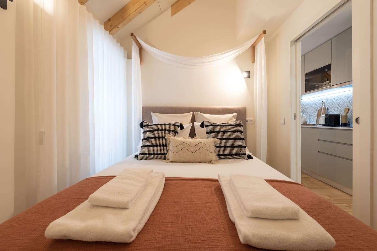 A bedroom with a bed, pillows, and a bedside table.