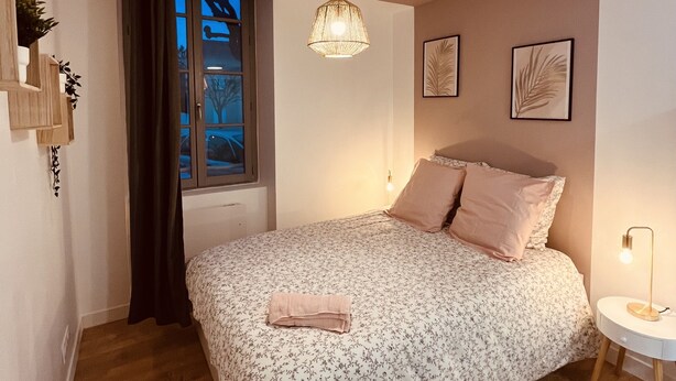 A bedroom with a bed, a window, a hanging light fixture, and a nightstand. - 🌟 Cosy Gannat 🌟 (Gannat)