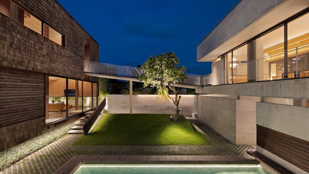 Un edificio moderno con piscina, un pequeño jardín y un árbol.