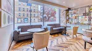 A modern interior with sofas, chairs, a coffee table, and a bookshelf. - Hub By Premier Inn London Clerkenwell (London)
