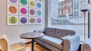 A modern interior with a sofa, a round table, and a wall with circular artwork. - Hub By Premier Inn London Clerkenwell (London)