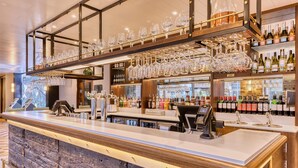 A bar area with a wooden counter, wine bottles, and glasses on shelves. - Hub By Premier Inn London Clerkenwell (London)