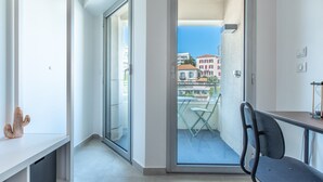 Ein Balkon mit freiem Blick auf Gebäude und einem Stuhl.