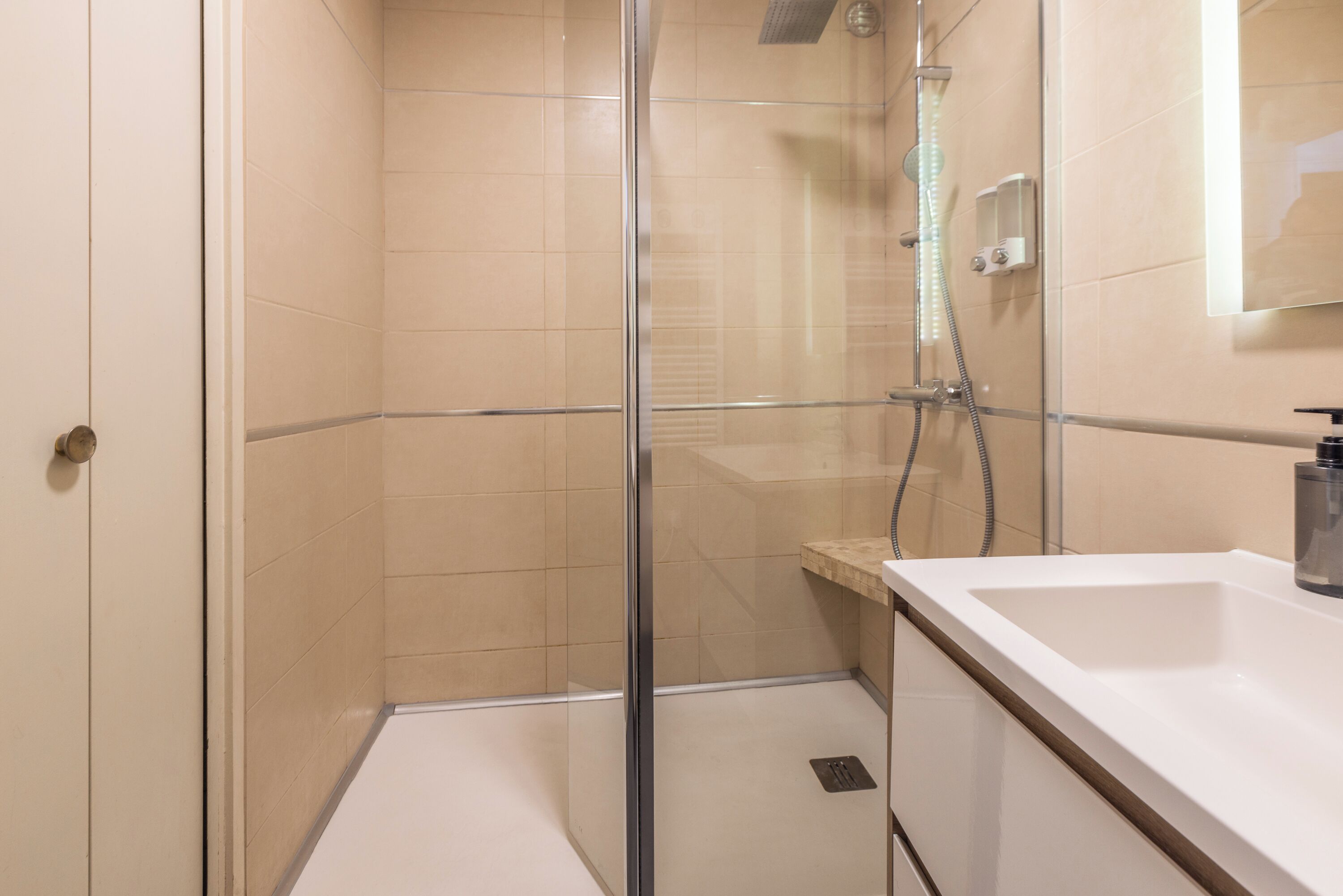 A modern bathroom with a glass-enclosed shower, a white sink, and a mirror above the sink.