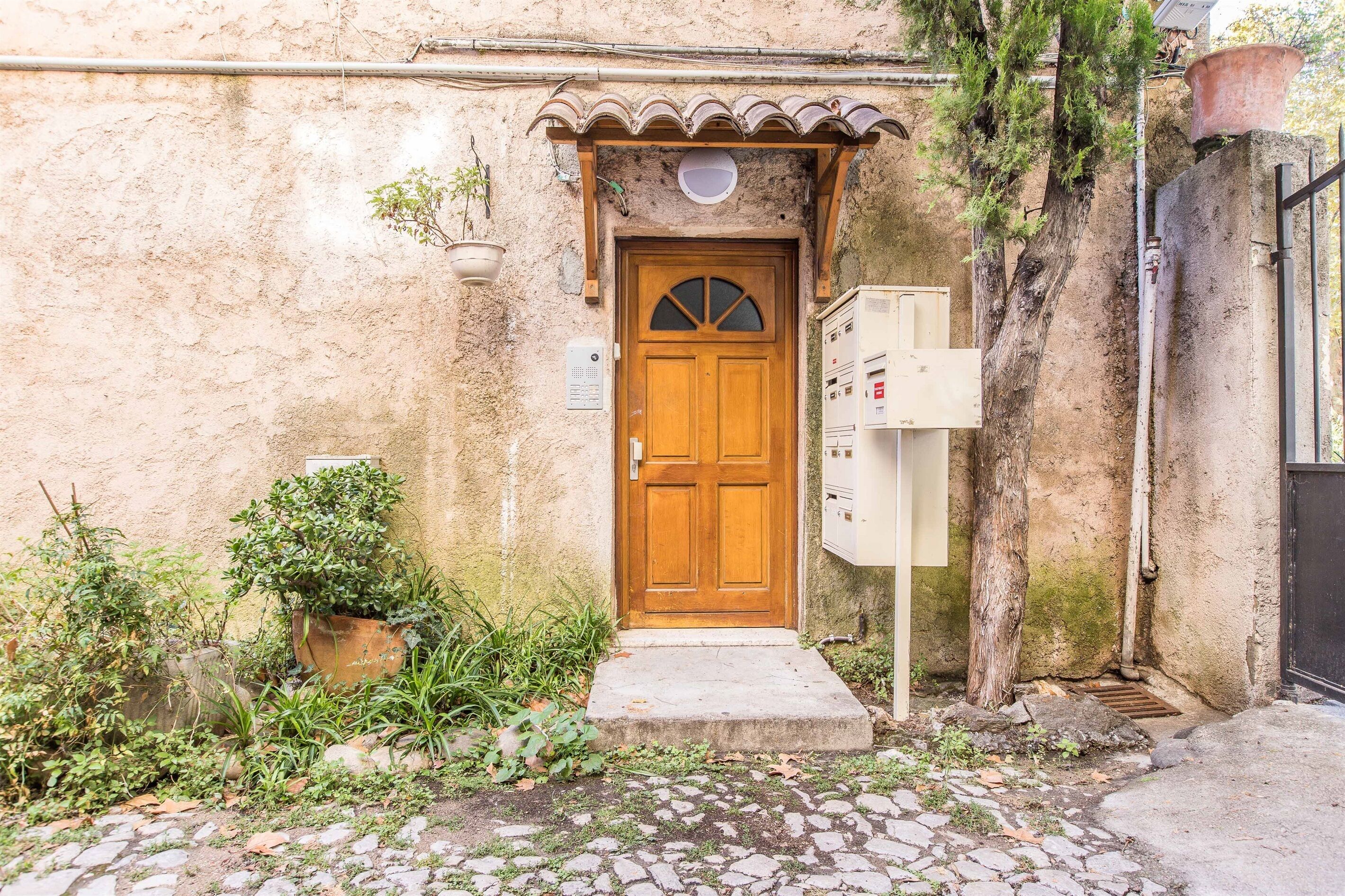 Un edificio rustico con una porta in legno, un piccolo portico e un armadietto utenze.
