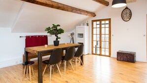 Un coin repas avec une table en bois, quatre chaises, une plante en pot et une horloge au mur.