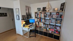Ett rum med ett skrivbord, en dator och en stor bokhylla full med böcker och dvd-skivor.