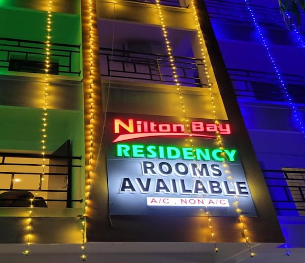 A sign for 'Nilton Bay Residency' with 'Rooms Available' and 'A/C, Non A/C' options.