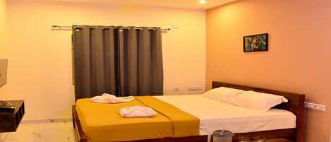A hotel room with a bed, a bedside table, a ceiling fan, and a window with curtains.