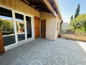 Ein Gebäude mit einer gefliesten Terrasse, einer Holztür und einem Schild mit einem Namen.