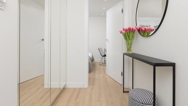A hallway with a bed, a chair, a console table with a mirror, and a vase of flowers. - Spacious Apartment | Center | Workspace | Balcony (Warszawa)