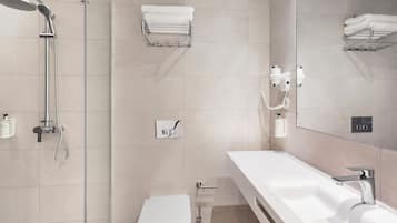 A modern bathroom with a shower, toilet, and a large sink.