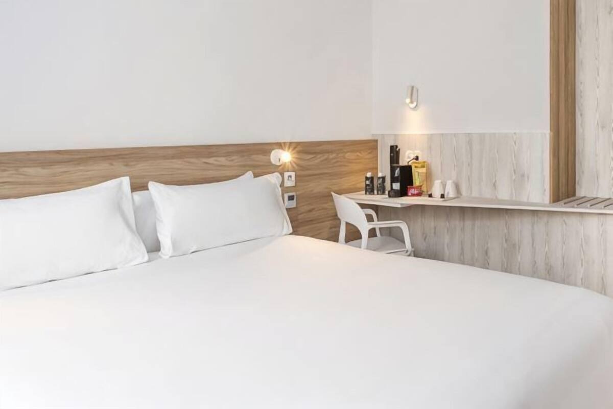 Une chambre d’hôtel avec un lit, un bureau et une chaise.