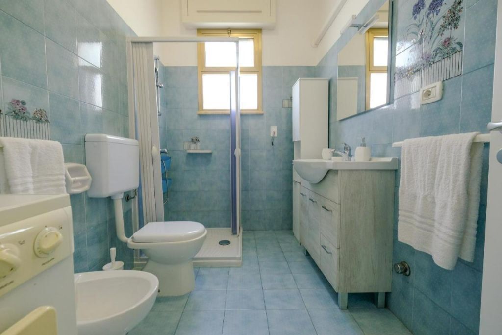 A bathroom with a toilet, bidet, sink, and shower.