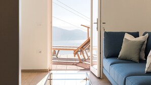 Et værelse med en blå sofa, en træterrasse og udsigt til bjerge.