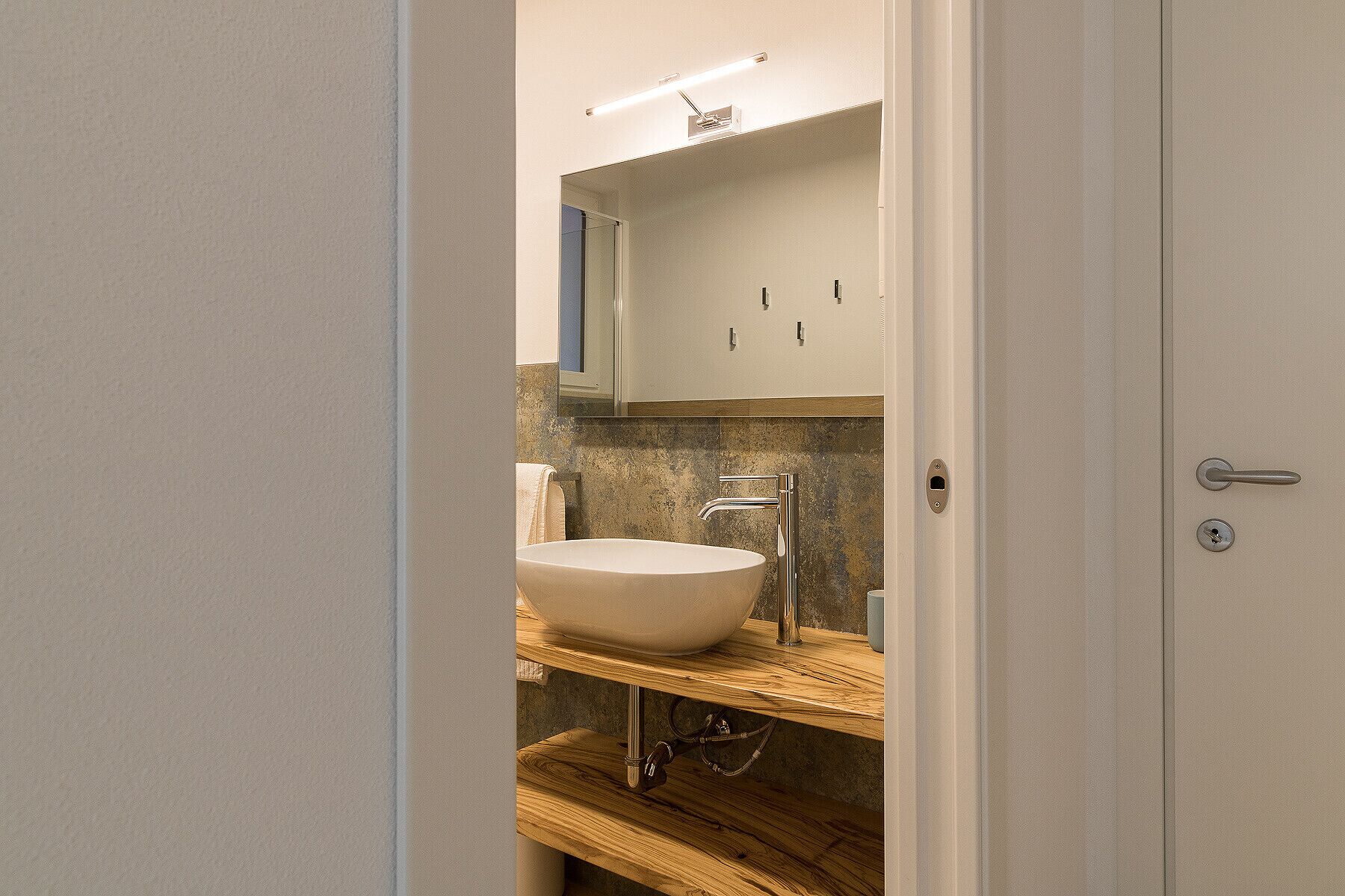 Ein modernes Badezimmer mit einem großen Waschbecken, einem Spiegel und einer Holz-Kommode.